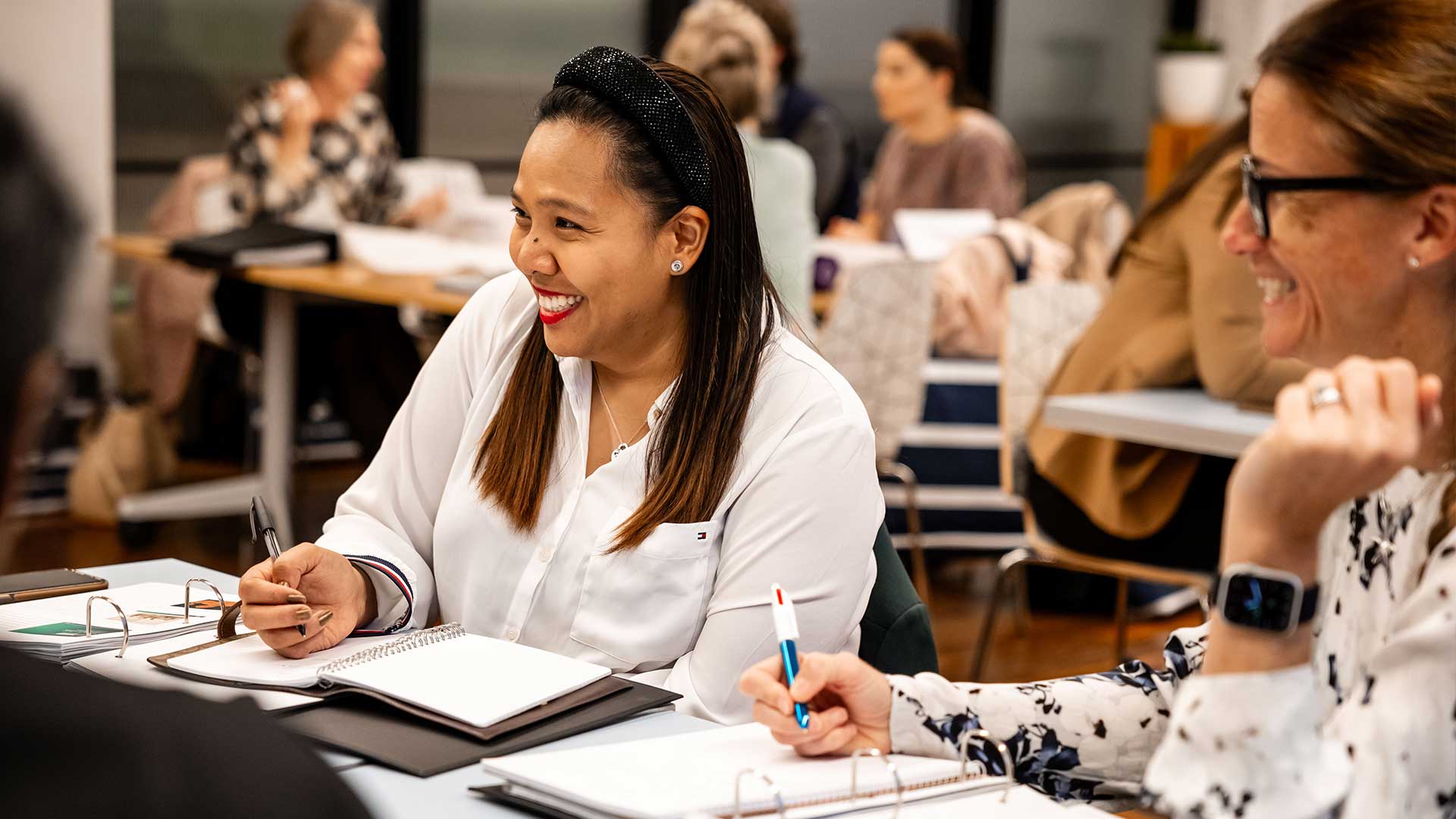 Woman sitting at a desk smiling at the person across from her